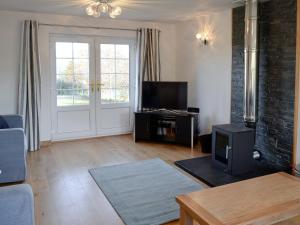 a living room with a couch and a tv at Carron House in Lochcarron