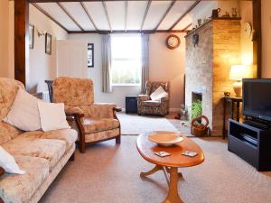 a living room with a couch and a fireplace at Pams Plaice in Offord Cluny