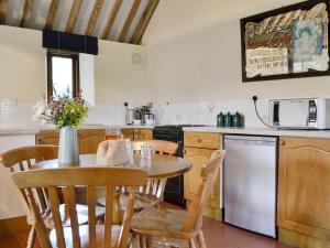 uma cozinha com uma mesa e cadeiras, uma mesa e um frigorífico em The Carthouse em Malmesbury