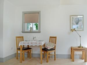 einem Esstisch mit 2 Stühlen und einem Fenster in der Unterkunft Geordies Byre in Mill of Fortune