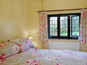 a bedroom with a bed and a window at Violet Cottage in Catfield