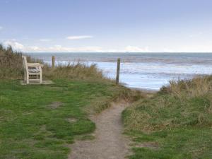 a chair sitting on a hill next to the ocean at Violet Cottage in Catfield