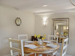 a dining room table with chairs and a clock on the wall at Violet Cottage in Catfield