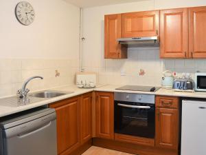 a kitchen with wooden cabinets and a sink and a stove at Little Fox Cottage in Levisham