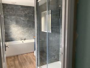 a bathroom with a shower and a bath tub at Little Fox Cottage in Levisham