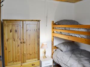 a bedroom with a bunk bed next to a night stand at Summer House in St Asaph