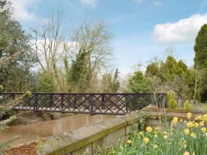 a bridge over a river with yellow flowers at Riverside in Alcester