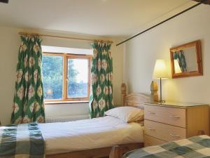 a bedroom with two beds and a window with curtains at Stable Cottage in Oswestry