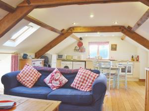 a living room with a blue couch and a kitchen at Stable Cottage in Oswestry