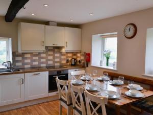 a kitchen with a table with chairs and a clock on the wall at Wickwoods in Wath