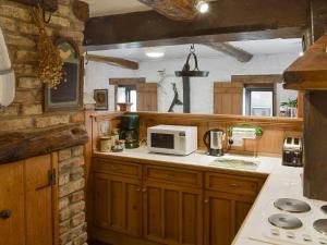 een keuken met houten kasten en een witte magnetron bij Threshing Barn - Kza in Glaisdale