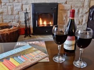 two glasses of wine on a table with a fireplace at Bryn Euryn Cottage - 28135 in Llandrillo-yn-Rhôs