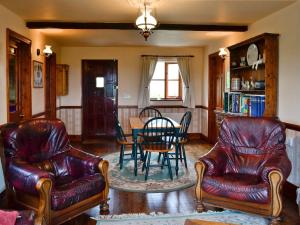 a living room with two leather chairs and a table at Woods Cottage in Evershot