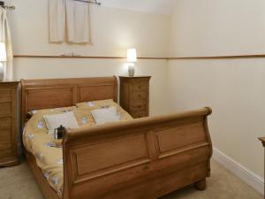 een slaapkamer met een houten bed in een kamer bij Barn Owl - 27820 in Westleigh