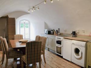 a kitchen with a table and chairs and a stove and oven at Symbister Suite in Turriff