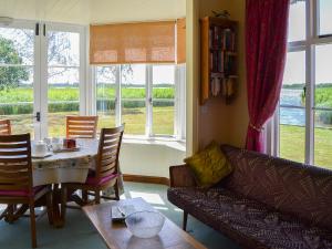 a living room with a table and a couch and windows at The Studio in Hickling