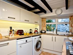 a kitchen with a washing machine and a window at Pilgrims Cottage in Brixham