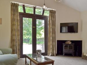 a living room with a large window and a tv at Waterfall Cottage in Tansley