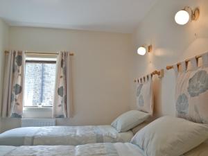 a bedroom with two beds and a window at Waterfall Cottage in Tansley