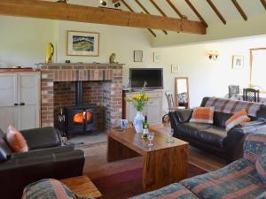 a living room with couches and a fireplace at Old Dairy Barn in Playden