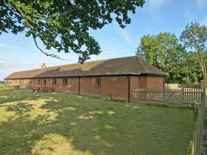 a red brick building with a fence in a yard at Old Dairy Barn in Playden