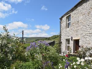 a stone house with flowers in front of it at Lilac Cottage in Muker