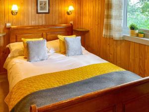 a bedroom with a wooden bed with yellow sheets and pillows at The Goyle-e4528 in Uplowman