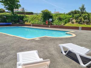 a swimming pool with two lounge chairs next to it at Honeysuckle Cottage in Woolacombe