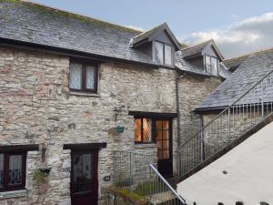 an old stone house with a staircase in front of it at Honeysuckle Cottage in Woolacombe