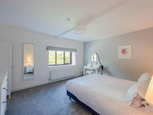 a white bedroom with a bed and a window at The Farmhouse in High Catton