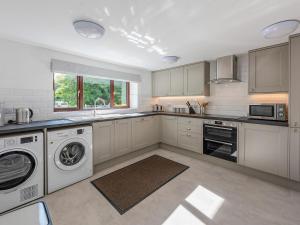 a kitchen with white cabinets and a washer and dryer at The Farmhouse in High Catton