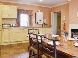 a kitchen with a wooden table with chairs and a tableablish at Laundry Cottage in Uldale