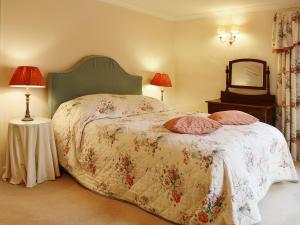a bedroom with a bed with a floral bedspread and a mirror at Laundry Cottage in Uldale