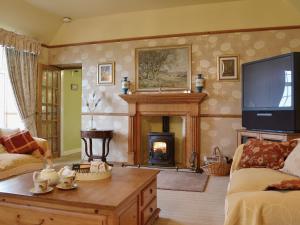 a living room with a fireplace and a tv at Gordons Hall Cottage in Carnbee