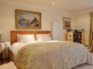 1 dormitorio con 1 cama y una pintura en la pared en Gordons Hall Cottage, en Carnbee