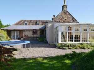 een huis met een trampoline in de tuin bij Gordons Hall Cottage in Carnbee