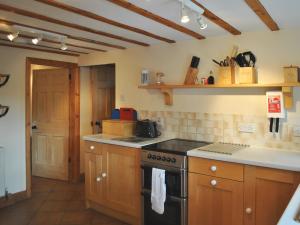 a kitchen with wooden cabinets and a stove top oven at Gunluk Cottage in Brompton