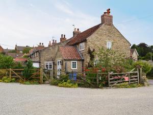 an old house with a wooden fence in front of it at Gunluk Cottage in Brompton