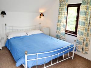 a bedroom with a bed with blue sheets and a window at Suncroft in Praa Sands