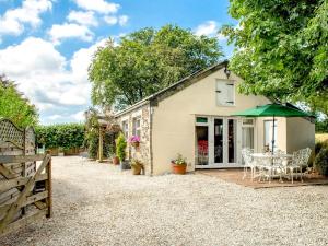 a cottage with a table and a green umbrella at Blackberry Cottage in North Hill