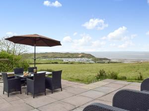a patio with a table and chairs and an umbrella at Brynymor Cottage in Llangennith