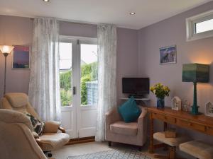 een woonkamer met een deur en een stoel en een televisie bij Little Croxley in Wroxall