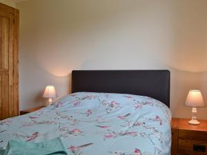 a bedroom with a bed with a blue comforter and two lamps at Y Gorlan in Llanllechid