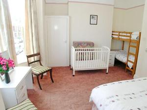 a bedroom with two beds and a crib and a crib at Mayflower in Cromer