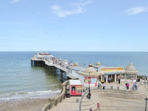a pier with people walking on the beach and the ocean at Mayflower in Cromer