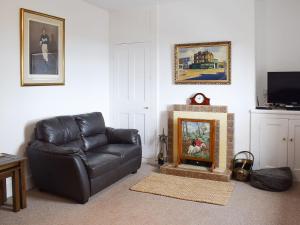 a living room with a leather couch and a fireplace at Little Lismoy in Sandown