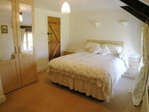 um quarto branco com uma cama e uma porta em Buzzard Barn em Saint Martins Green