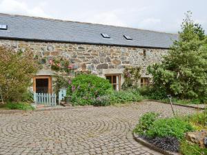 a stone house with a brick driveway in front of it at Buzzard Barn in Saint Martins Green