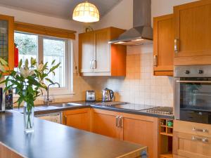 a kitchen with wooden cabinets and a vase of flowers on the counter at Tigh A Vullin - S4628 in Ardfern