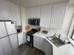 kuchnia z białymi szafkami, kuchenką i zlewem w obiekcie Ocean View Loft w mieście Glendale